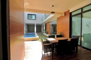 Eine moderne Terrassenanlage im Freien mit Pool, Holzbelag und Essbereich mit Stühlen und Tisch.