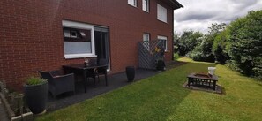 A brick house with a patio area, outdoor seating, and a fire pit.