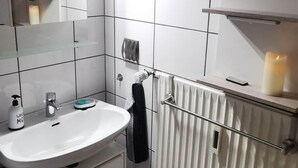 A modern bathroom with a white sink, mirror, and a towel rack. There are two framed motivational posters on the wall.