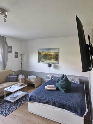 A modern bedroom with a bed, a sofa, a coffee table, and a painting on the wall.