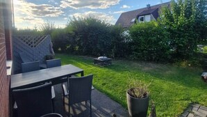 A patio with outdoor furniture, a garden, and a view of a house.
