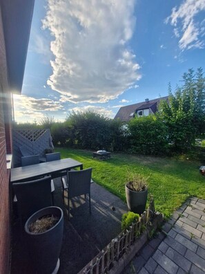 A patio with outdoor furniture, a garden, and a view of a house.