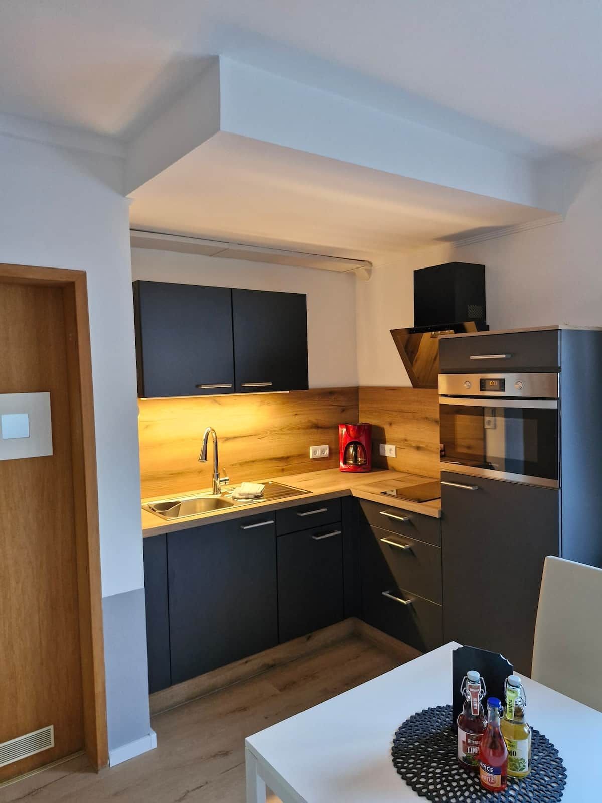 Una cucina moderna con mobili scuri, una cappa aspirante in acciaio inossidabile e un forno integrato.