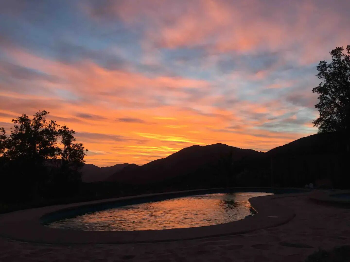 Ein Sonnenuntergang über einer Berglandschaft mit einem Schwimmbecken.