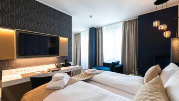 A hotel room with a bed, bedside table, TV, and a window with curtains.