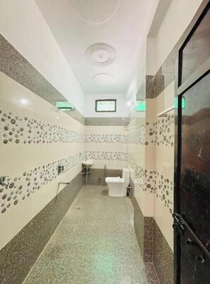 A bathroom with a decorative patterned wall, toilet, and small window.