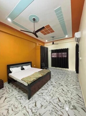 Relax in this stylish room with a large bed, ceiling fans, and air conditioning for a comfortable stay.