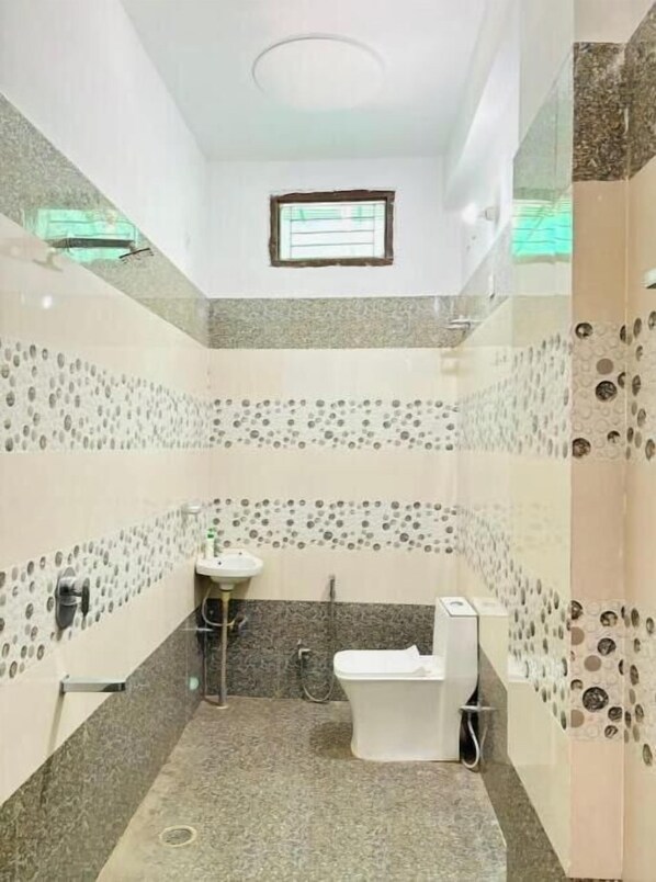 Bathroom features a toilet, sink, and shower area, with decorative wall patterns and a speckled tile floor.
