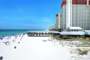 A beach resort with high-rise buildings, a sandy beach, and a clear blue sky.