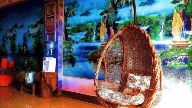A wicker chair with a floral cushion in a room with a mural of a tropical landscape. - Dali Shuanglang Caiyunjian Inn (Dali City)