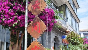 A building facade with hanging wooden signs with red text, surrounded by vibrant pink bougainvillea flowers. - Dali Shuanglang Caiyunjian Inn (Dali City)