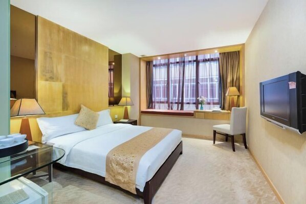 A hotel room with a bed, bedside tables, a TV, a window with curtains, and a desk with a chair.