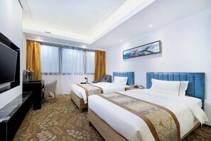 A hotel room with two beds, a flat-screen TV, a desk, and a painting on the wall.