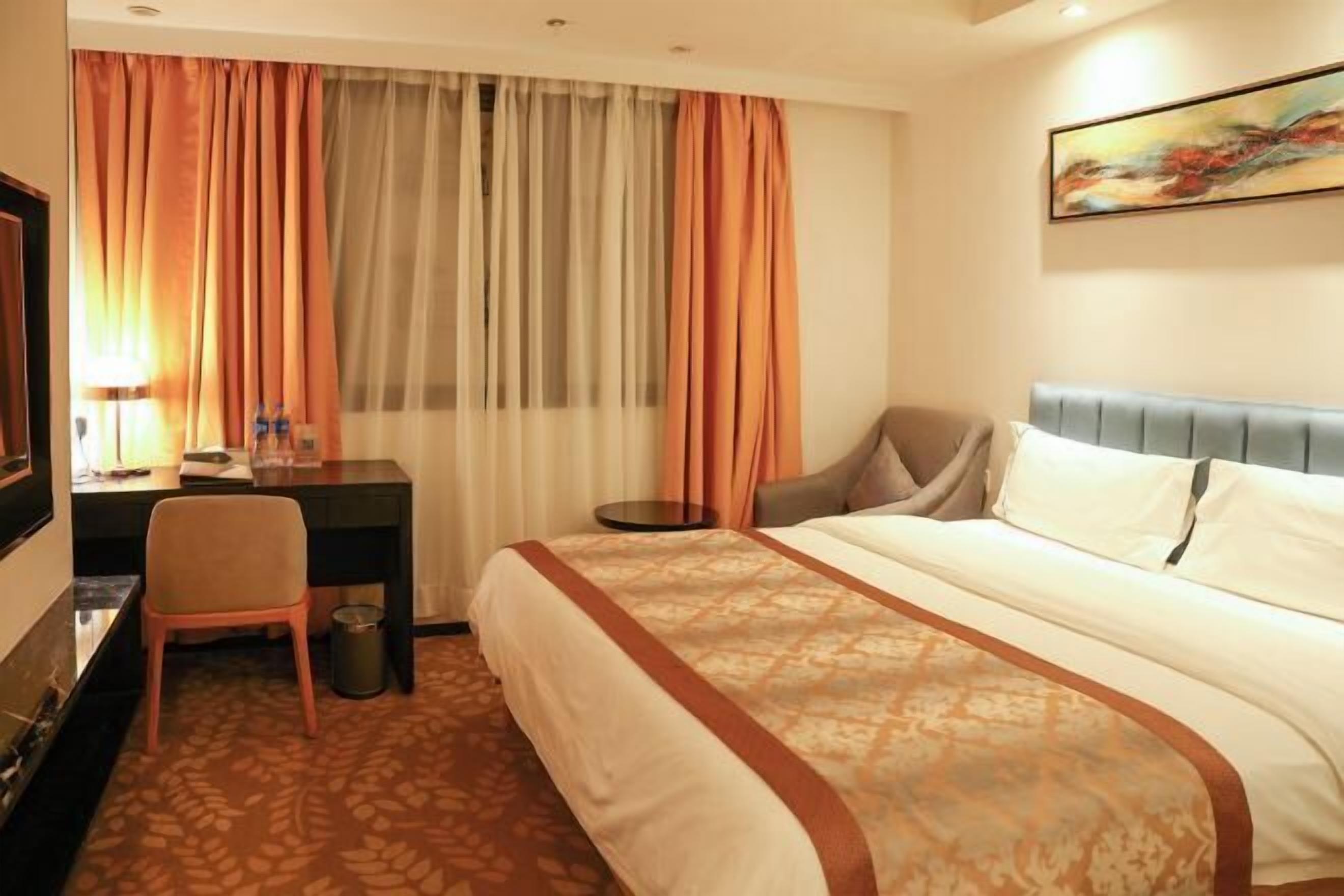 A hotel room with a bed, desk, chair, and a television.