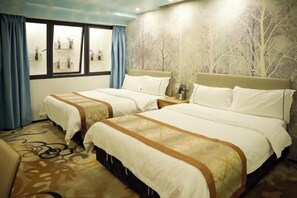A hotel room with two beds, a large window with curtains, and a wall mural of trees.