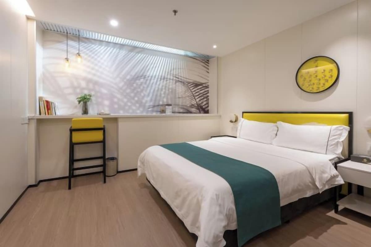 A bedroom with a bed, bedside table, window, and a desk with a chair.