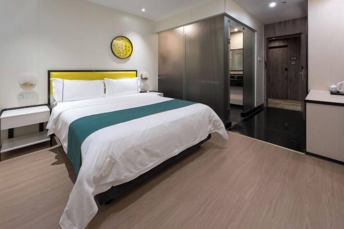 A hotel room with a bed, a nightstand, a wardrobe, and a bathroom.