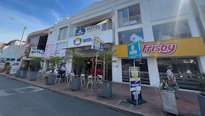 A hotel with a sign indicating 24-hour service, a commercial center, and a restaurant named 'Frisby'.
