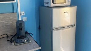 A compact kitchenette with a stainless steel refrigerator, a microwave on top, and a coffee maker on the counter. - Appartement 25 m² Avec Petite Terrasse (Cherbourg-en-Cotentin)