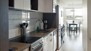 Una cocina moderna con electrodomésticos de acero inoxidable, armarios de madera y un comedor con mesa y sillas.