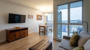 Una sala de estar moderna con un televisor de pantalla plana, muebles de madera, un comedor y un ventanal con vistas.