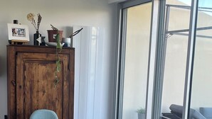 Ein Essbereich mit Holztisch, vier Stühlen, einer Vitrine mit Dekoration und Blick durch große Schiebeglastüren auf einen Außenbereich.