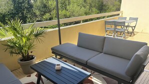 Ein Balkon mit einer Couch, einem kleinen Tisch und einem Blumentopf.