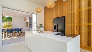 A modern kitchen with a central island, wooden paneling on the wall, and a built-in refrigerator. - Villa MENTA IV with pool (Linardići)