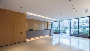 Eine geräumige Lobby mit einem Holzbüro, großen Fenstern mit Blick auf die Stadtlandschaft und einem glänzenden Boden.