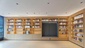 Eine moderne Bibliothek mit Holzbögen, einem zentralen Sitzbereich und einem großen Fenster.