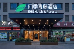A hotel entrance with a large sign for EHG Hotels & Resorts, a glass facade, and a well-lit entrance area.
