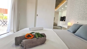 Hotellihuone, jossa on sänky, tyynyjä, yöpöytä, televisio ja taustalla näkyvä kylpyhuone.