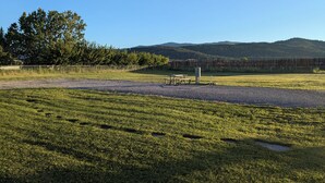 A grassy field with a picnic table and a fence in the background.