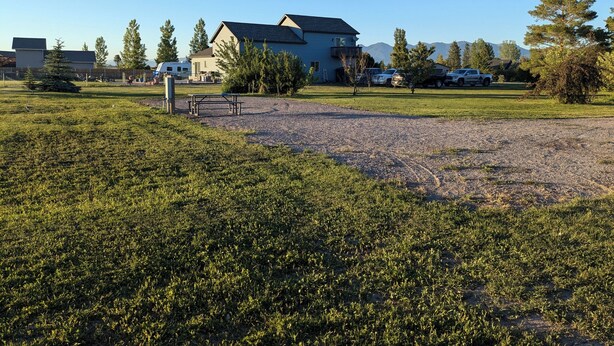 A residential area with a house, a picnic table, and a gravel area.