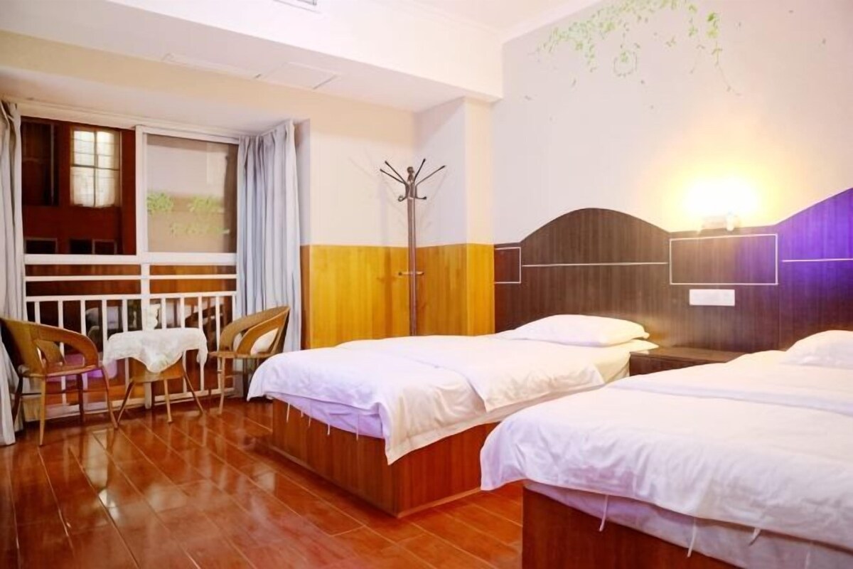 A hotel room with two beds, a table, and a chair.