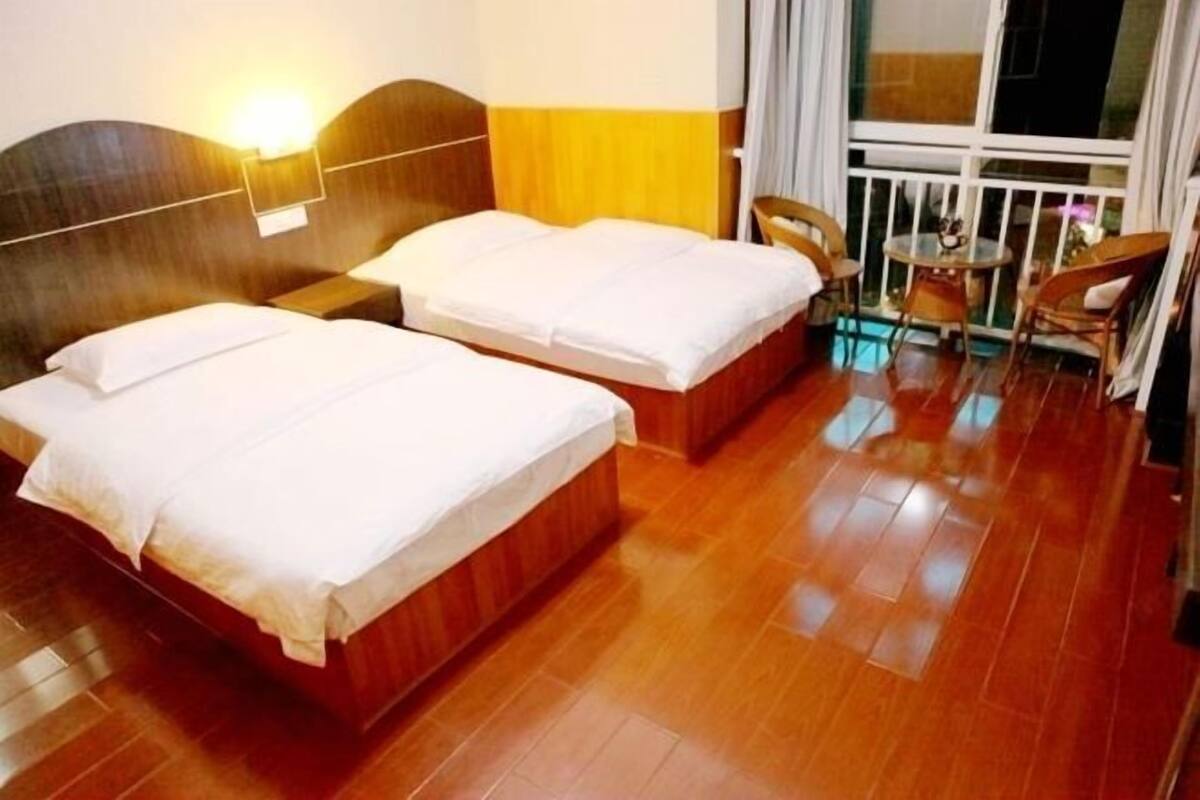 Ein Hotelzimmer mit zwei Betten, Holzboden, einem Balkon mit Korbstühlen und einem Nachttisch mit Lampe.