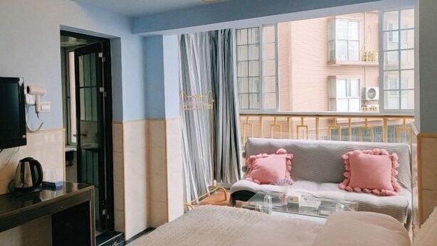 A hotel room with a bed, a bedside table, a TV, and a window with curtains.