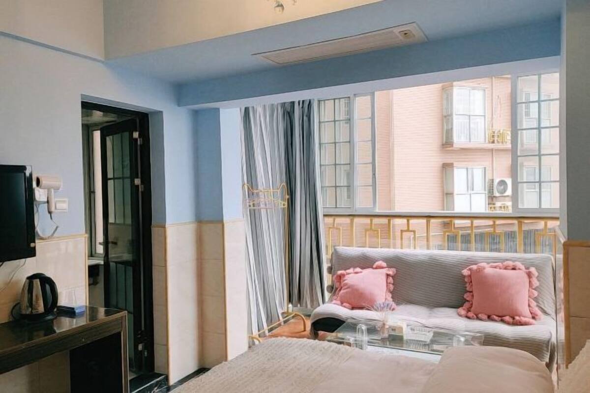 Ein Hotelzimmer mit Bett, Nachttisch, Fernseher und einem Fenster mit Vorhängen.