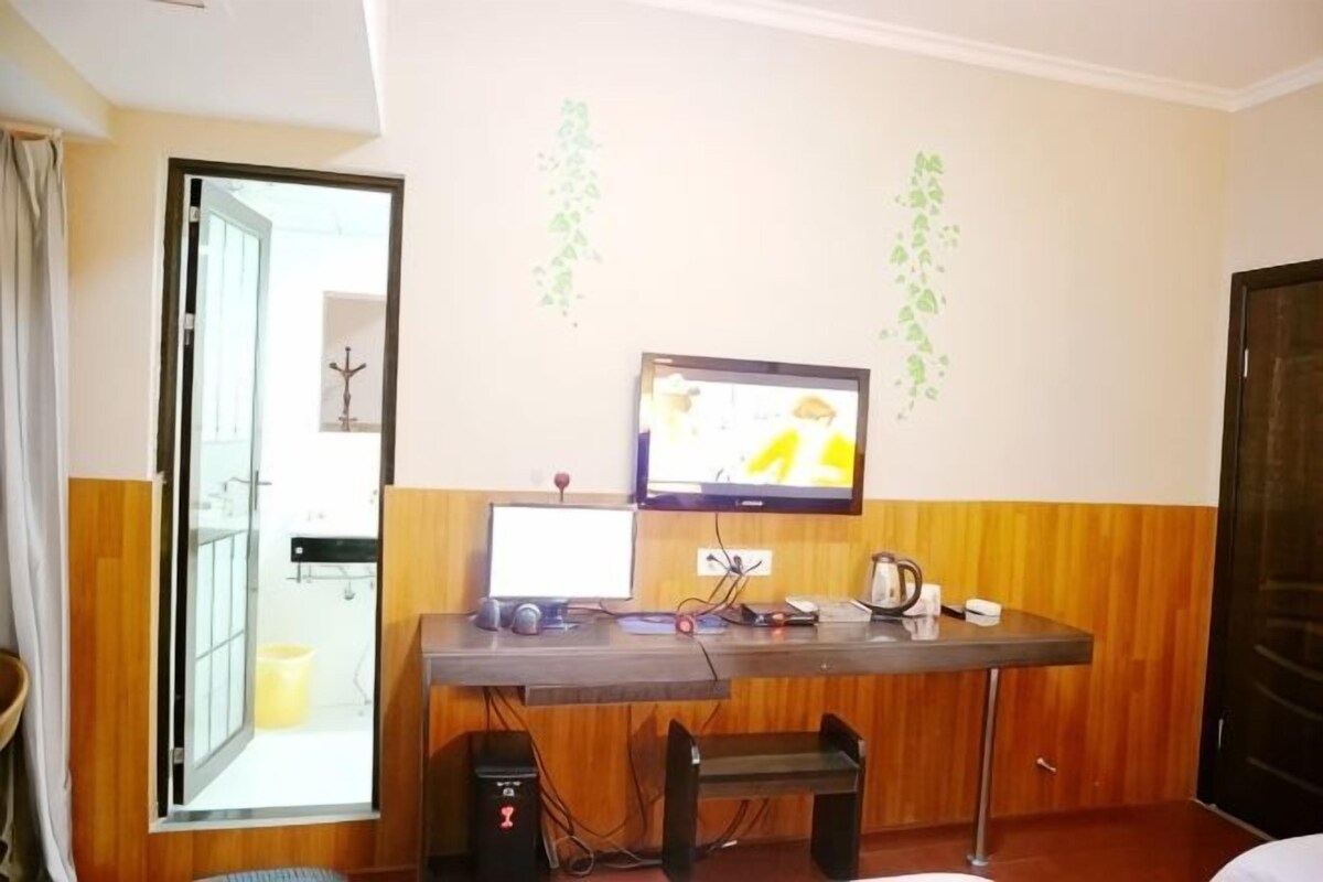 A room with a desk, a computer, a television, and a door.
