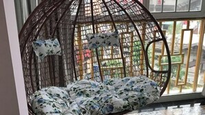 A hanging chair with floral cushions in a room with a view through a window. - Zhangjiajie Jiangnan Hotel (Zhangjiajie)