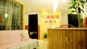 A reception area with a wooden reception desk, a sofa, and a wall with a sign.