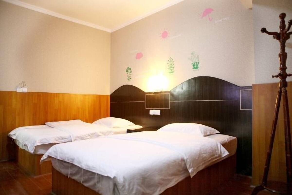 Ein Hotelzimmer mit zwei Einzelbetten, einem Holz-Kopfteil, einer Wandleuchte und Holzboden.