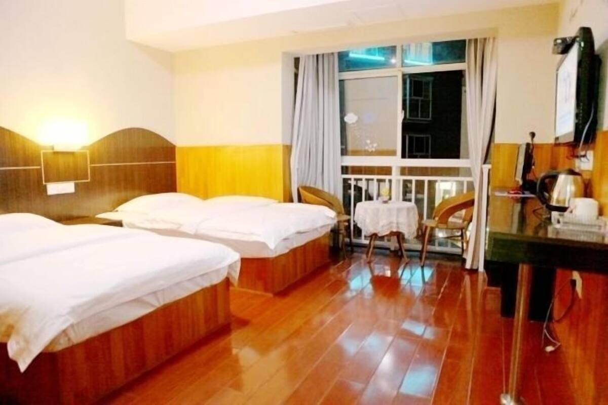 Ein Hotelzimmer mit zwei Einzelbetten, einem kleinen Tisch, einem Stuhl und einem Schreibtisch mit einem Computer.