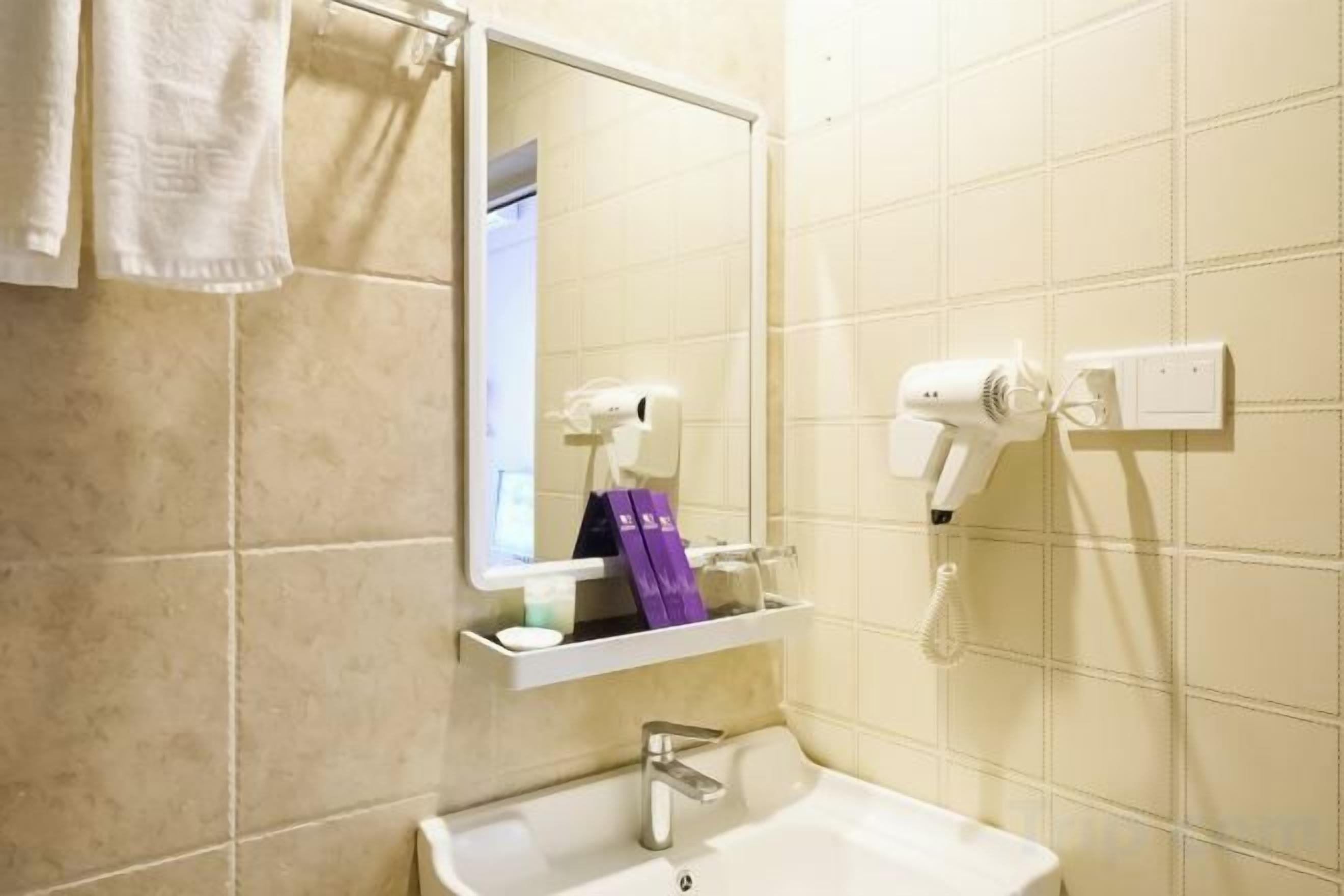 Casa de banho com lavatório, espelho, porta-toalhas e secador de cabelo.