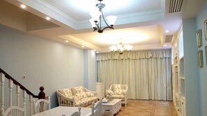 A spacious living room with a dining table, two sofas, a chandelier, and a staircase. - Dongshan Zhuolan Resort Hotel (Dongshan County)