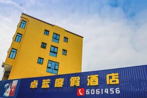 Un edificio amarillo con un letrero azul que muestra un número de teléfono.