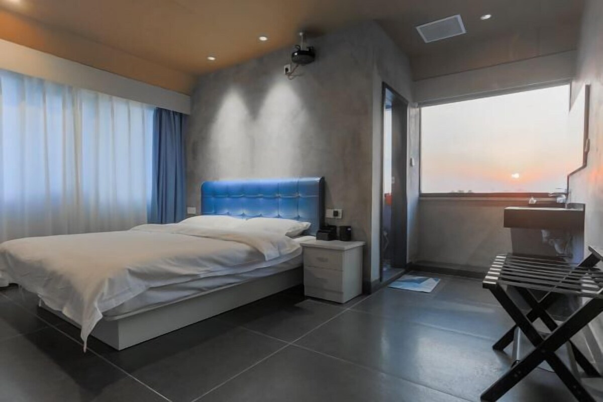 Un dormitorio moderno con cama, mesita de noche y un pequeño escritorio con silla.