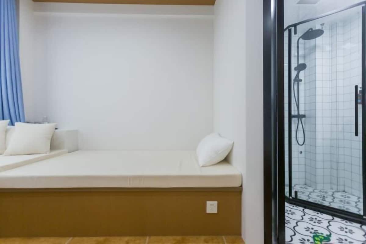 A room with a bed, a shower, and a tiled floor.