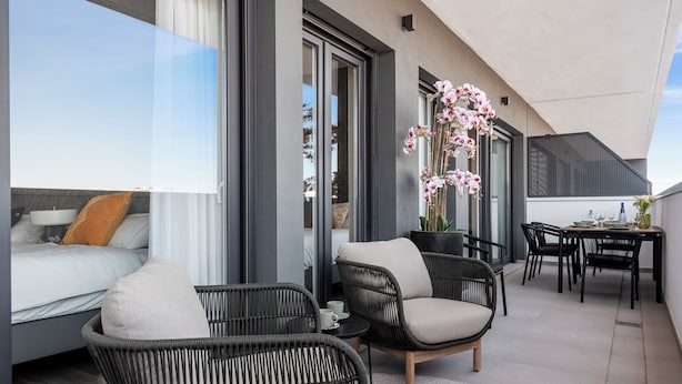 Un balcon moderne avec des fauteuils en osier, une table à manger et un canapé.