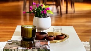 A dining table with a white tablecloth, a potted plant, a candle, and a tray with a teapot and cups. - Stylish Historic Home – Timeless Charm with Modern Touches (Bovina Center)